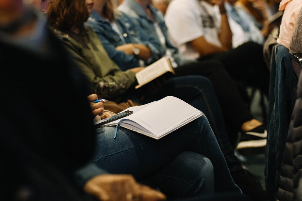 A group of professionals at a conference taking notes and using devices 